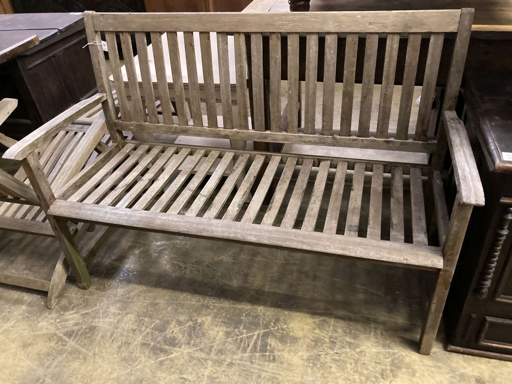 A weathered teak garden bench, length 129cm together with a teak steamer chair and nest of three teak rectangular garden tables